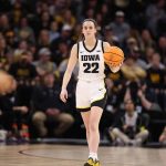 Photo of Caitlin Clark in her number 22 jersey holding a basketball during a game.